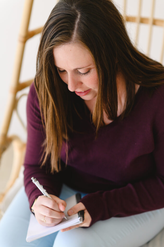 woman writing with pen on notebook